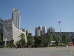 This photo was taken in Flower City Square, Guangzhou, Guangdong Province,China. On the left side of the picture, it is the Guangzhou Library. On the right side, it is the Guangdong Museum. Those buildings are the public fuction buildings. The government place this square in the city axis. Government hope people can spend their time in this square. But people do not like this square especially in the summer time. Guangzhou is in the subtropical area.This kind of square without tree shapes, people hope to pass it as fast as they can. It contrarys to democracy.